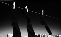 pair-of-black-socks-and-an-odd-one-hanging-on-a-washing-line-with-blue-sky-over-a-city-skyline-joe-fox